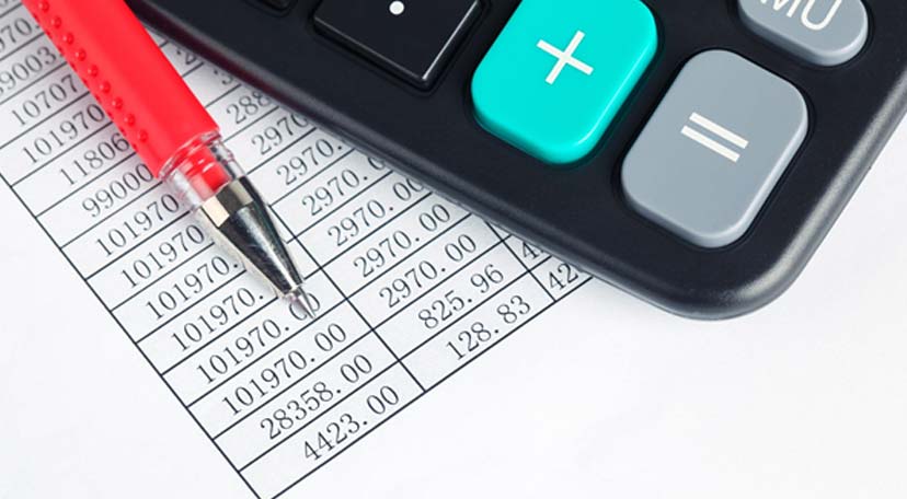 A-financial-report,-with-a-red-pen-and-a-calculator-on-top-of-it