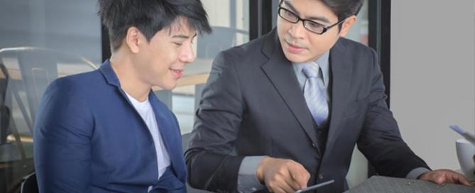 two-men-in-business-suits-having-a-discussion-while-holding-a-tablet